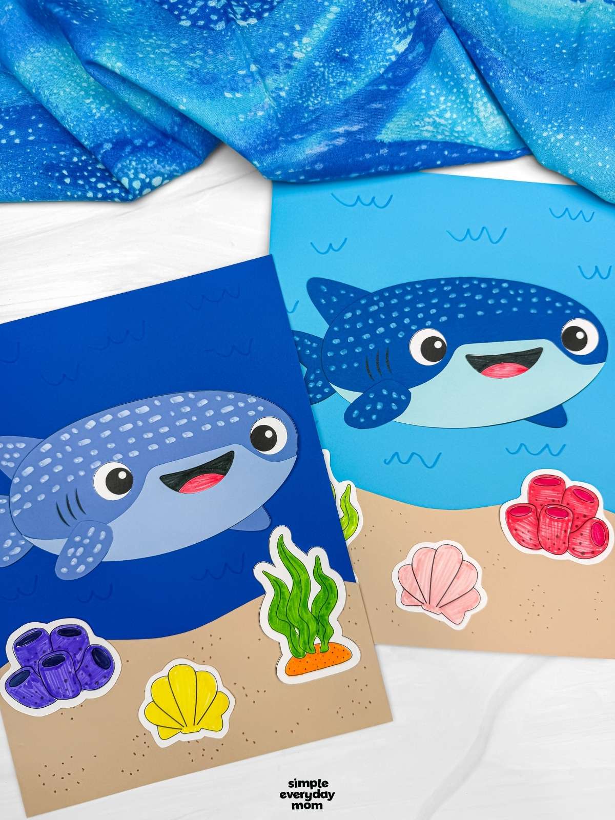A completed Craft showing two whale shark paper crafts on ocean themed backgrounds with seaweed, coral, and shell decorations.