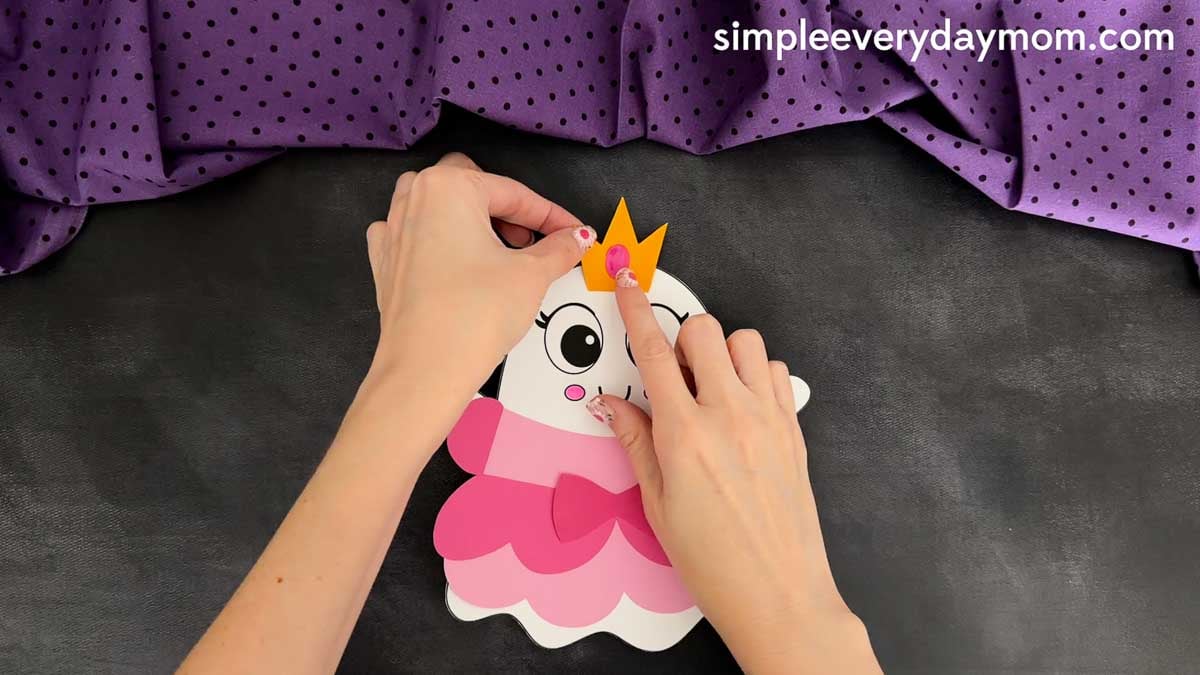 Hands coloring the jewel on the crown piece for the Princess Ghost Disguise Craft before attaching it above the ghost's head.