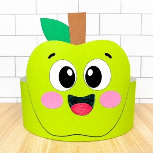 A completed craft of a green apple headband with a smiling face, leaf, and stem ready to wear.