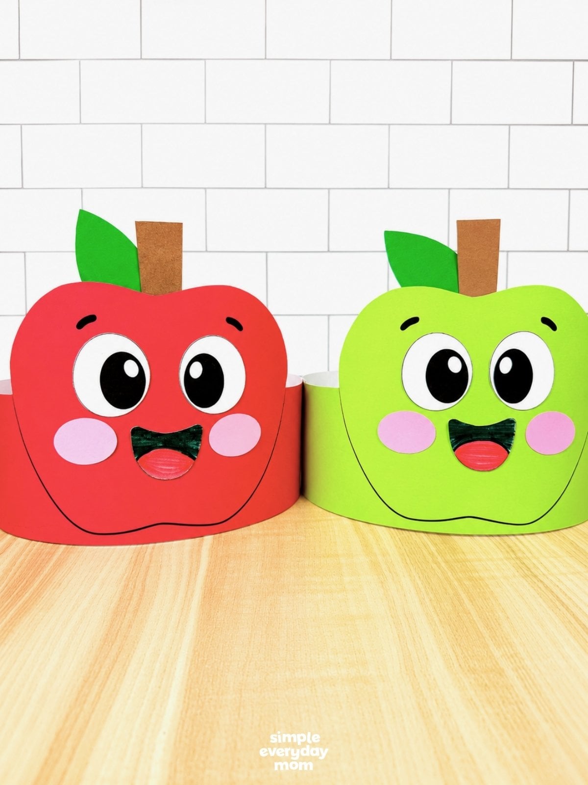 Side by side completed red and green apple headband crafts ready for fall classroom activities.