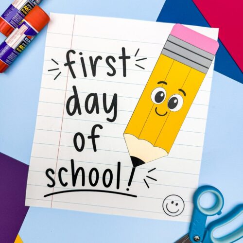 A completed craft featuring a smiling pencil on a first day of school notebook paper with craft supplies nearby.