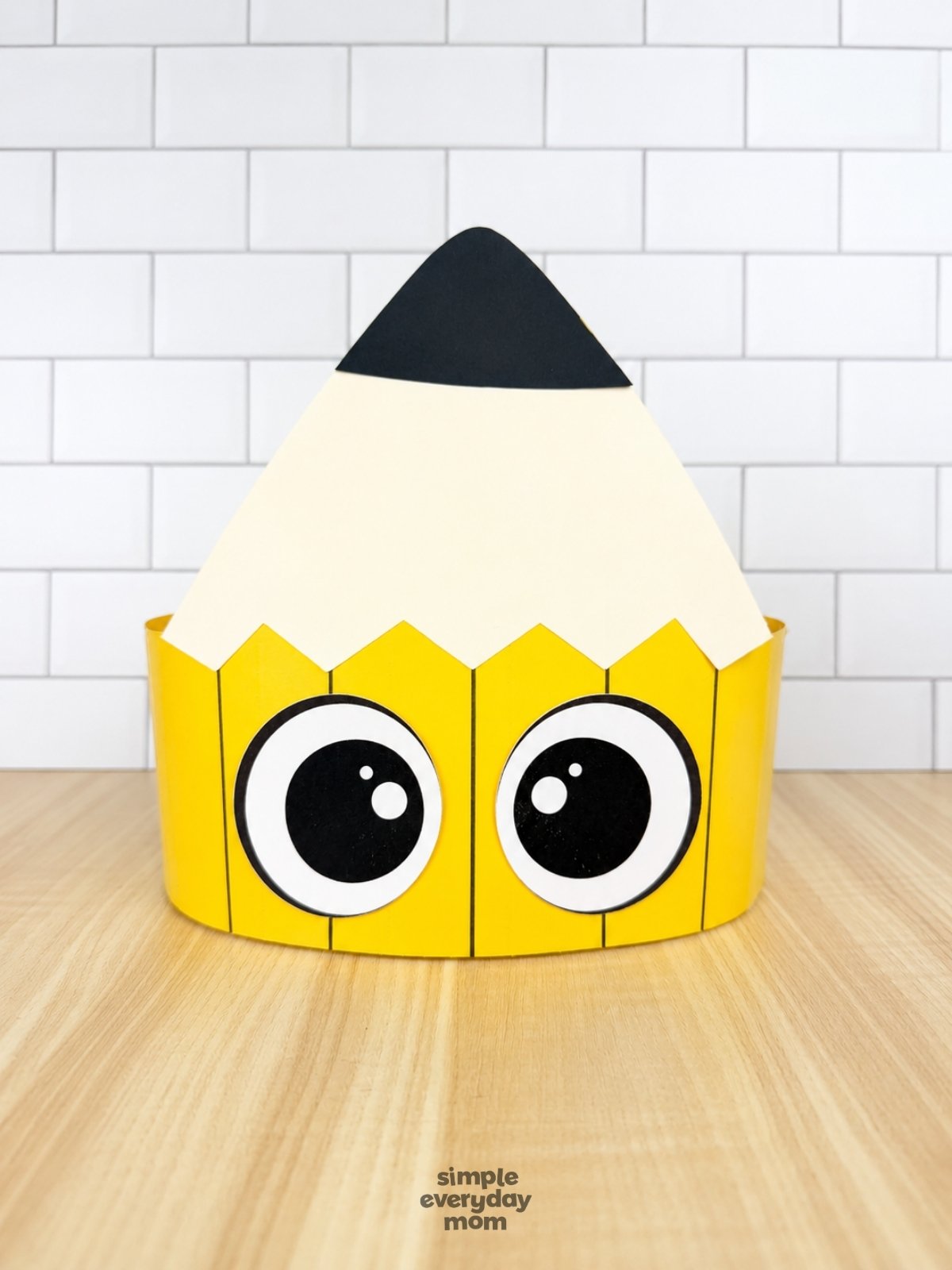 A completed craft of a printable pencil headband with large eyes displayed on a tabletop.