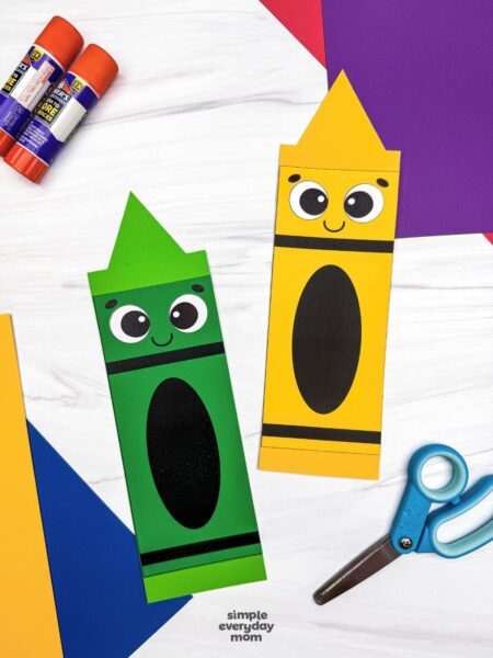 A completed crayon shape craft display with colorful paper, glue sticks, and scissors for a back to school activity.