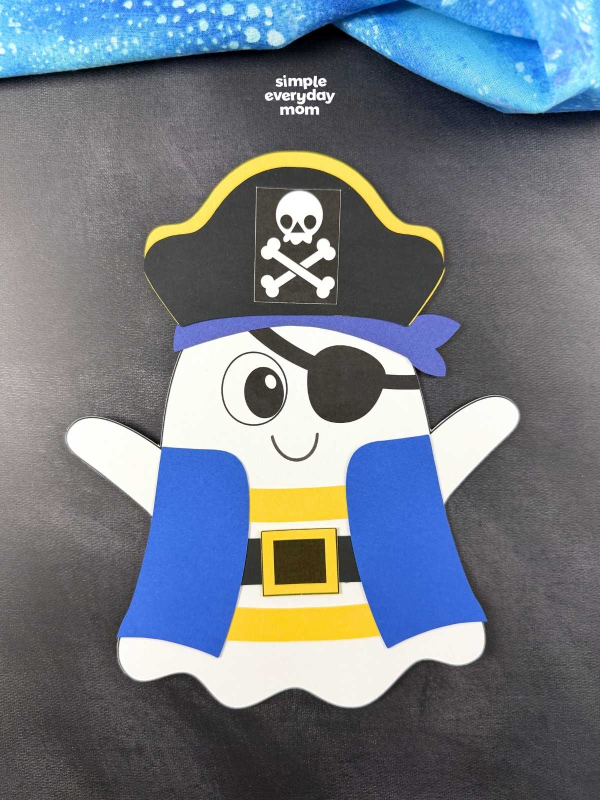 A completed craft of a pirate ghost disguise with a pirate hat, eye patch, striped shirt, belt, and blue pirate coat.