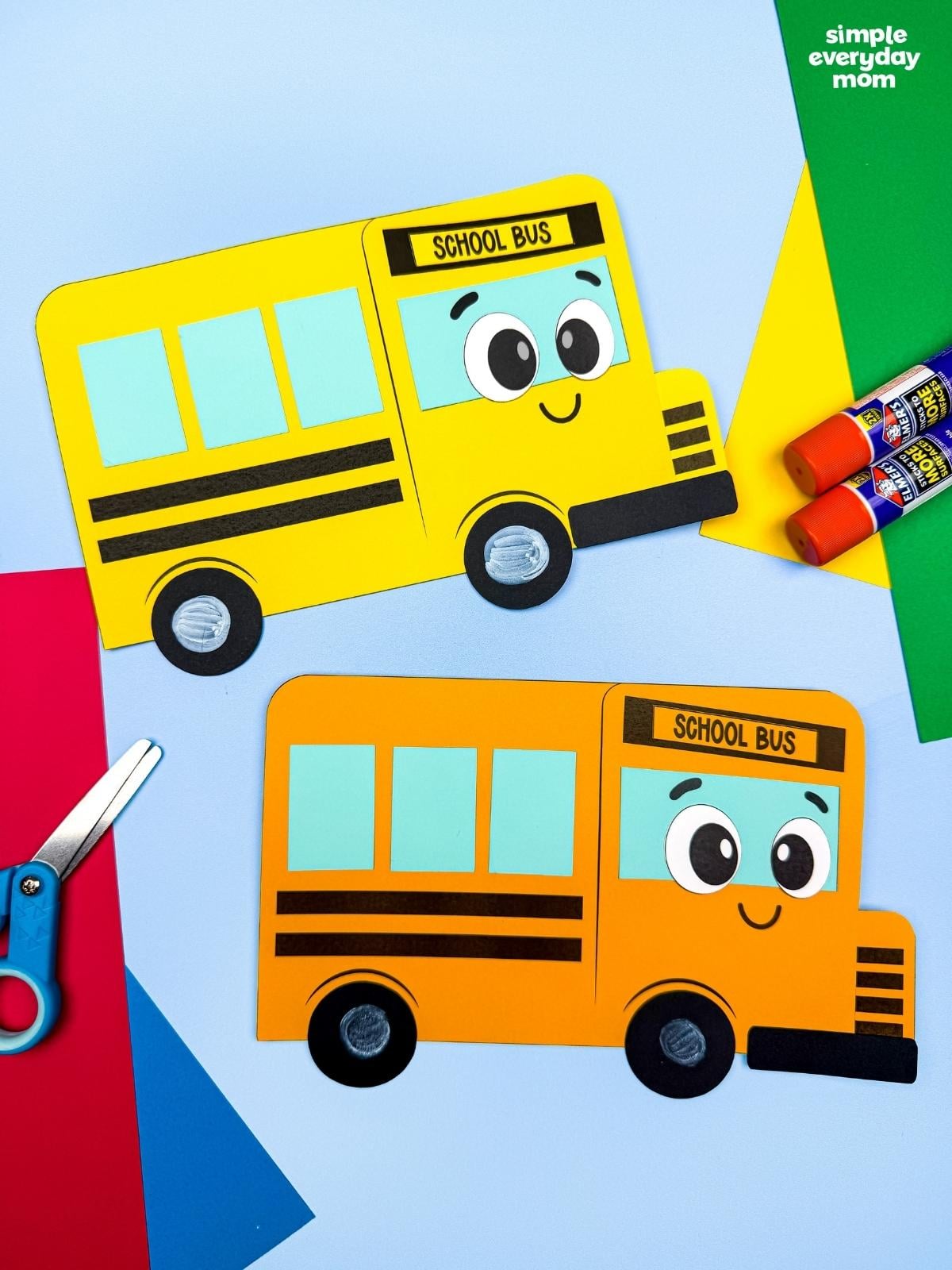 A completed craft showing two finished bus shape crafts made from colorful geometric shapes with school supplies near