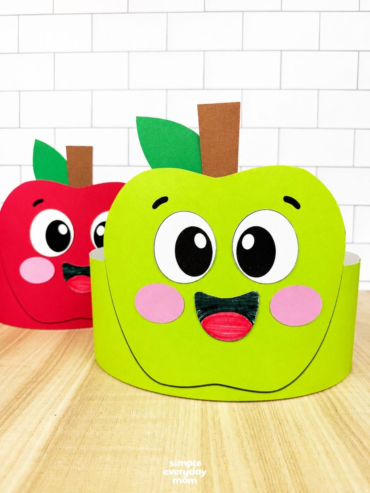 A completed craft showing green and red apple headband crafts displayed together for a fun fall classroom activity.