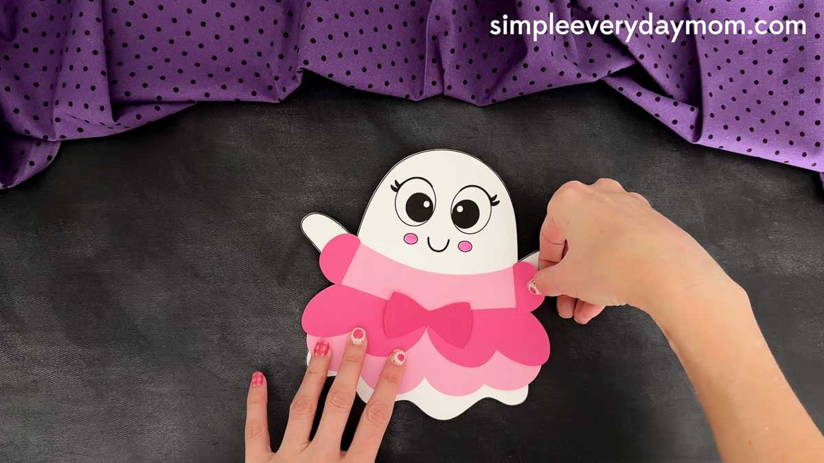 Hands placing the sleeve piece onto the right side of the princess dress, lining it up with the ghost's arm.