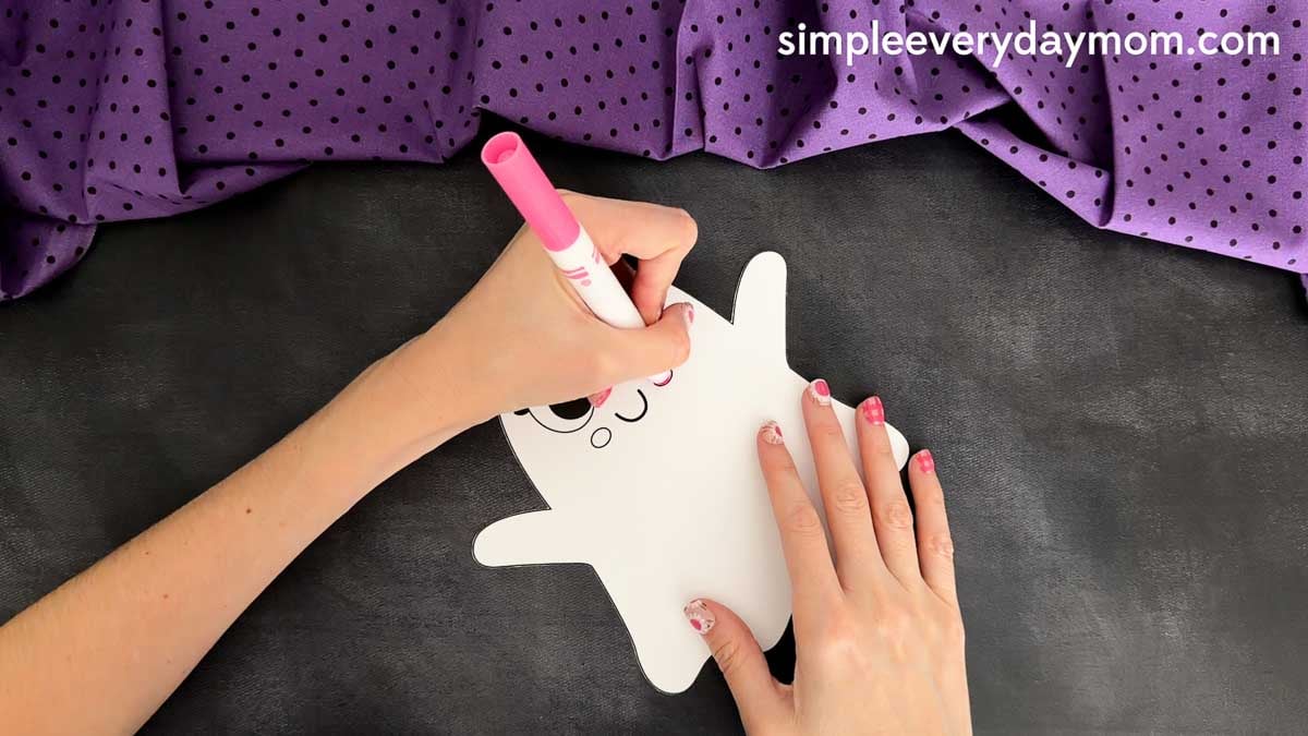 Hands coloring the Princess Ghost Disguise Craft face on the ghost body template before assembling the princess costume pieces.