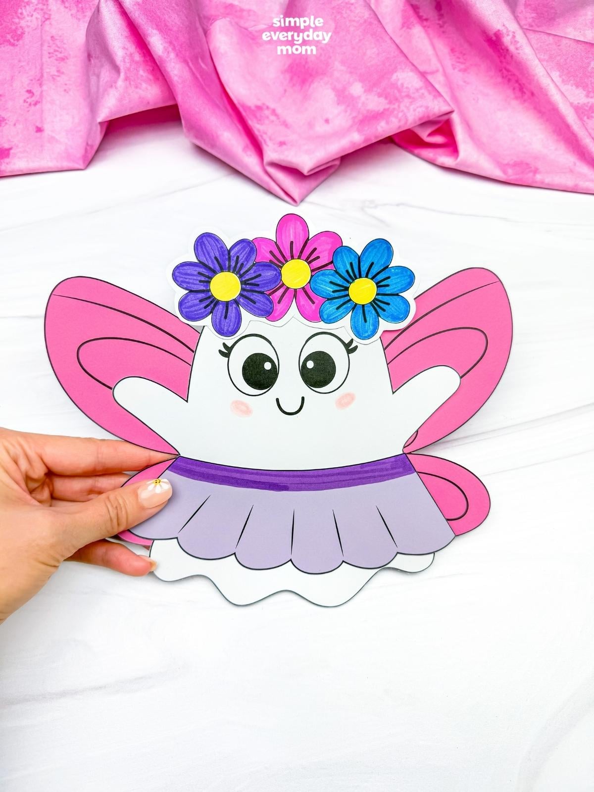 Hands holding the completed Fairy Ghost Disguise Craft with pink fairy wings, a flower crown, and a skirt.