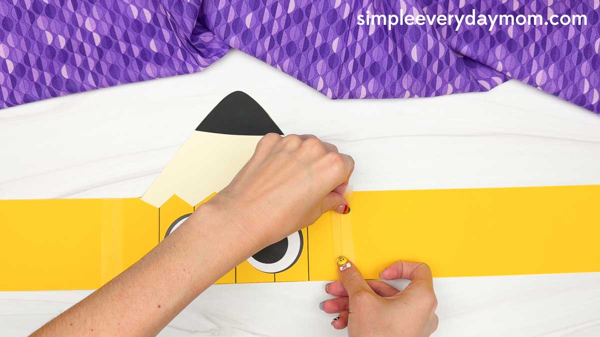 Hands connect the printable pencil headband strips to fit around a child's head.