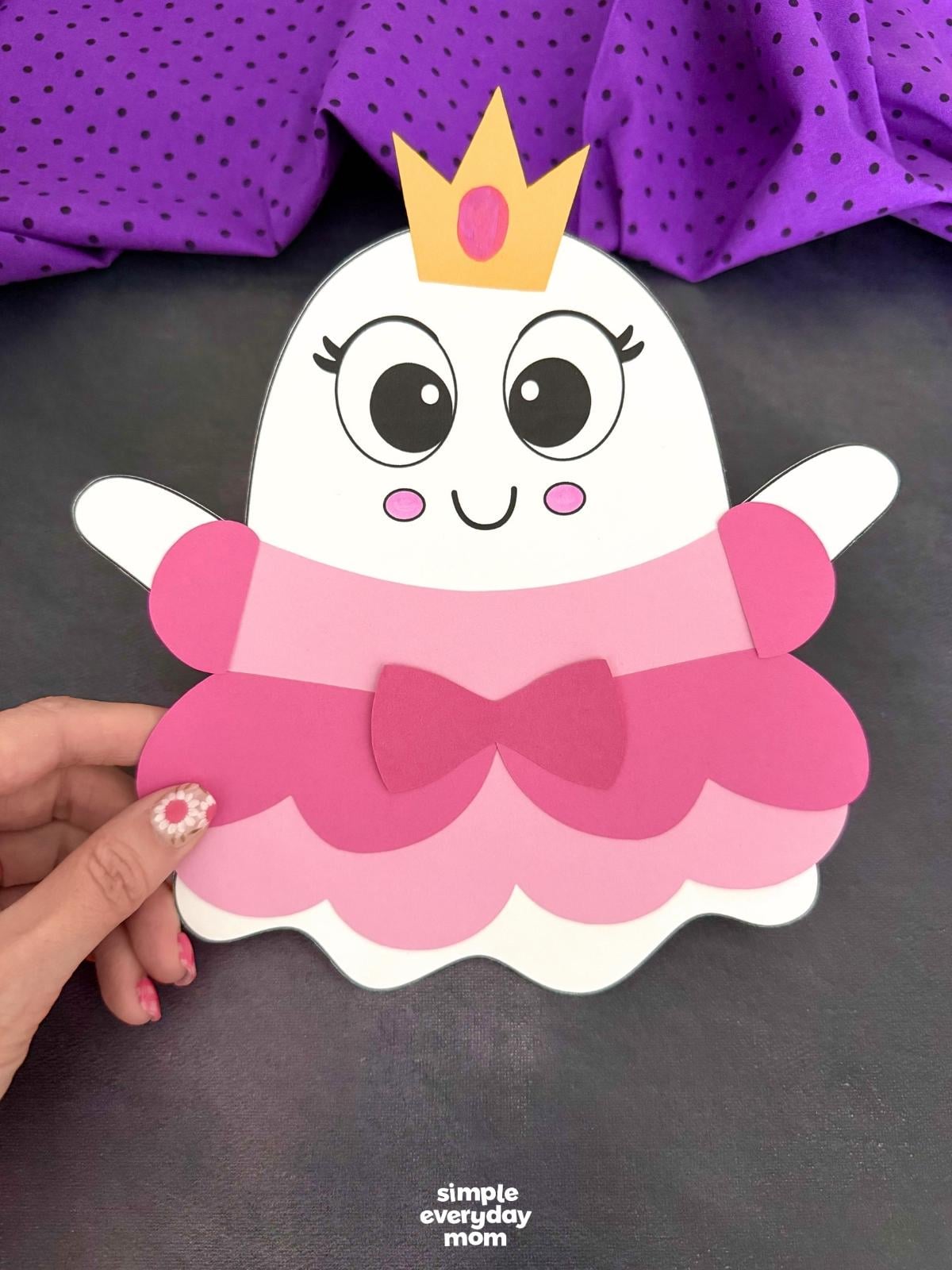 Hands holding the completed Princess Ghost Disguise Craft with a layered princess dress, bow, sleeves, and crown.
