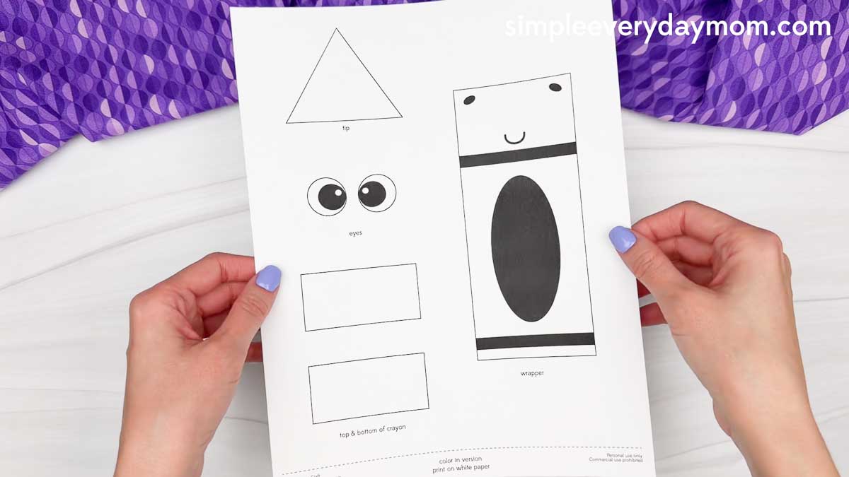 Hands holding the printable crayon shape craft template with labeled cut out pieces.