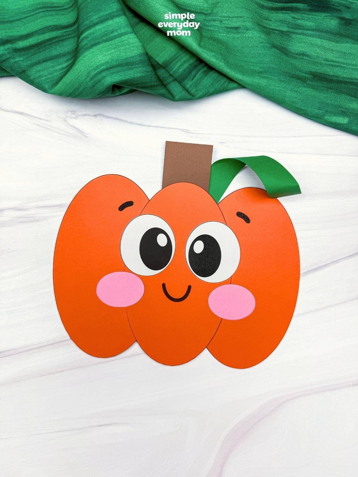 A completed Craft of a smiling Pumpkin Shape Craft with a curled vine, stem, and cheerful face.