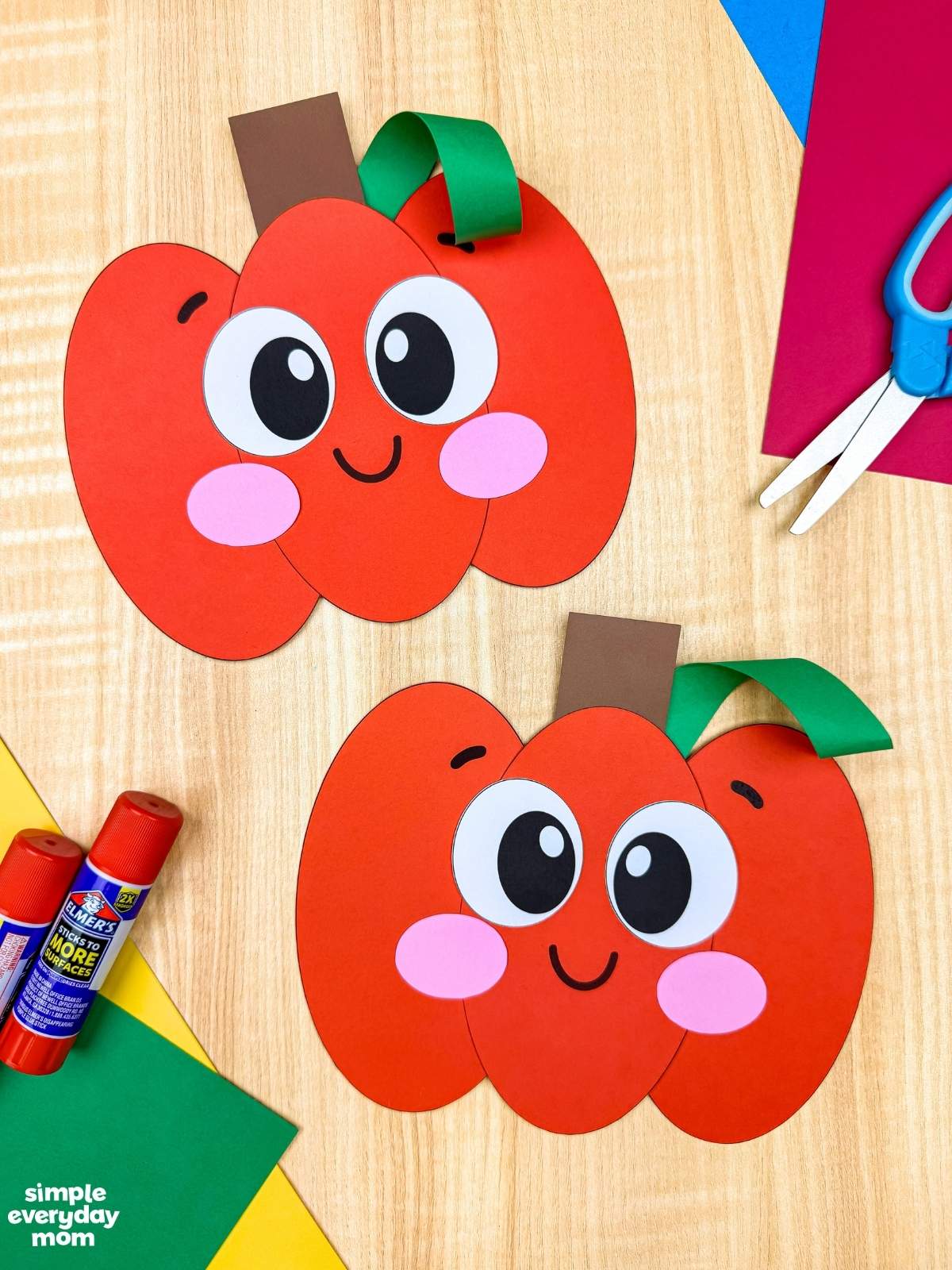 A completed Craft showing two Pumpkin Shape Craft designs displayed with colorful paper, scissors, and glue sticks.