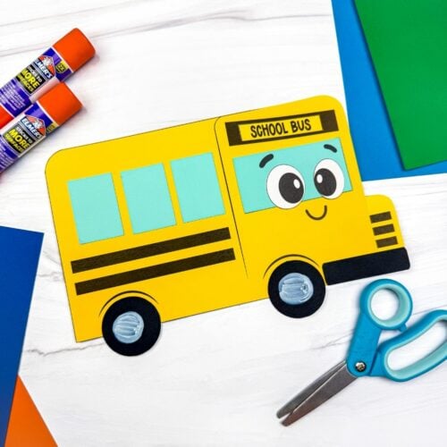 A completed craft showing the finished bus shape craft with colorful paper, scissors, and glue sticks nearby.