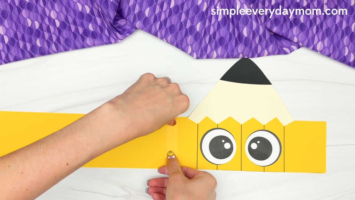 Hands attach the printable pencil headband extension strip to fit around a child's head.