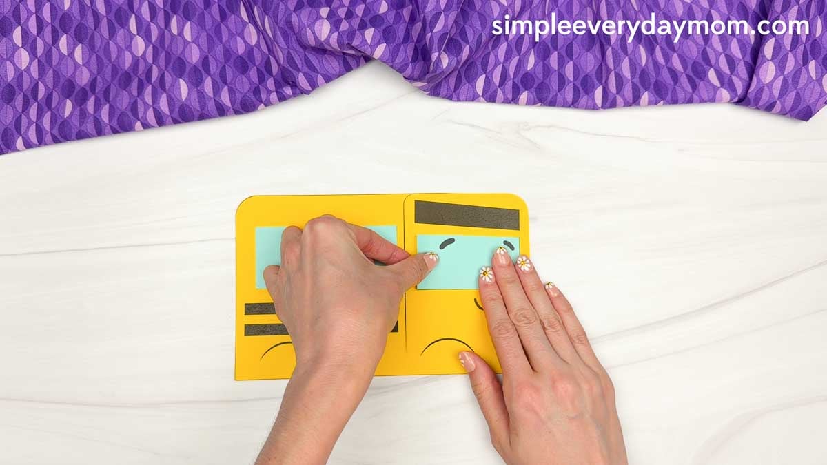 Hands placing the left eye onto the bus face below the eyebrows on the bus shape craft template.