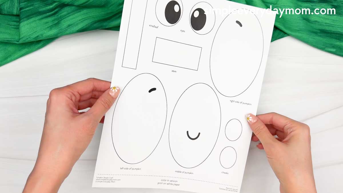 Hands holding the Pumpkin Shape Craft printable template with all the cut out pieces ready to assemble.