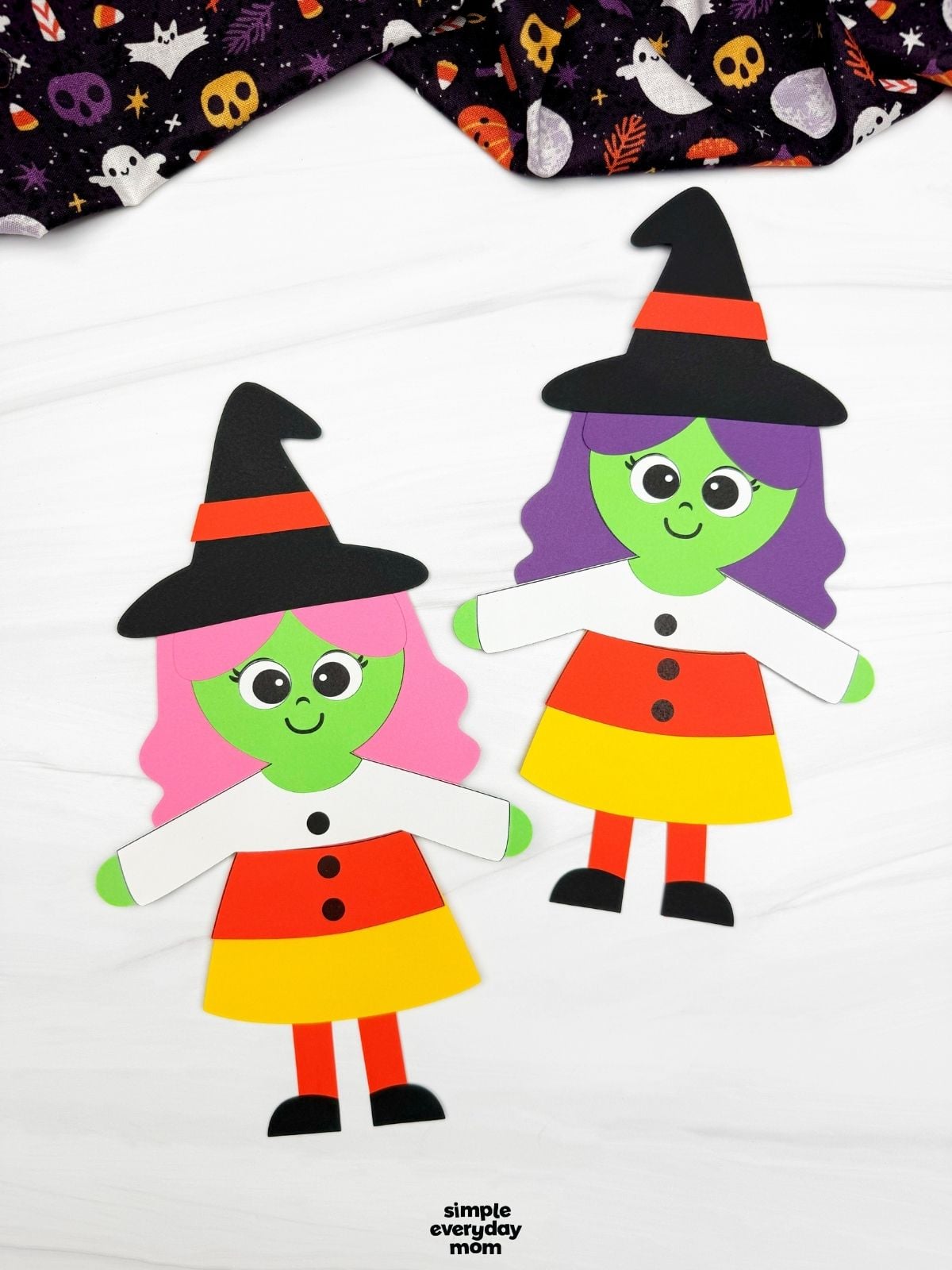 A completed craft showing two Witch Candy Corn Crafts with colorful hair, candy corn dresses, and witch hats.