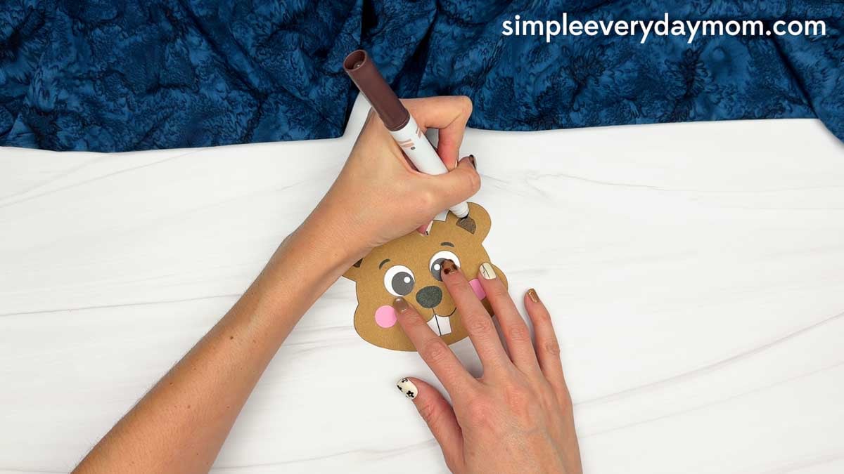 Hands using a marker to add details to the beaver’s ears for the Beaver Name Craft.