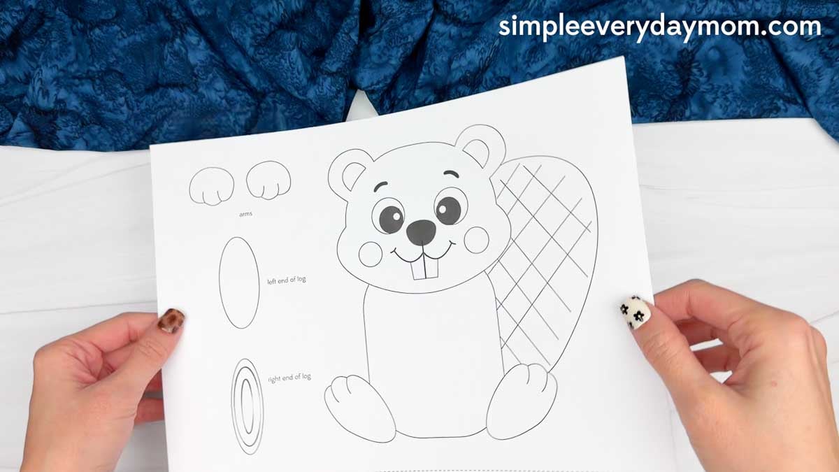 Hands holding a printable Beaver Name Craft template with beaver, arms, log ends, and tail pieces.