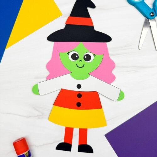 A completed craft showing a Witch Candy Corn Craft with pink hair, a witch hat, and a candy corn dress alongside craft supplies.
