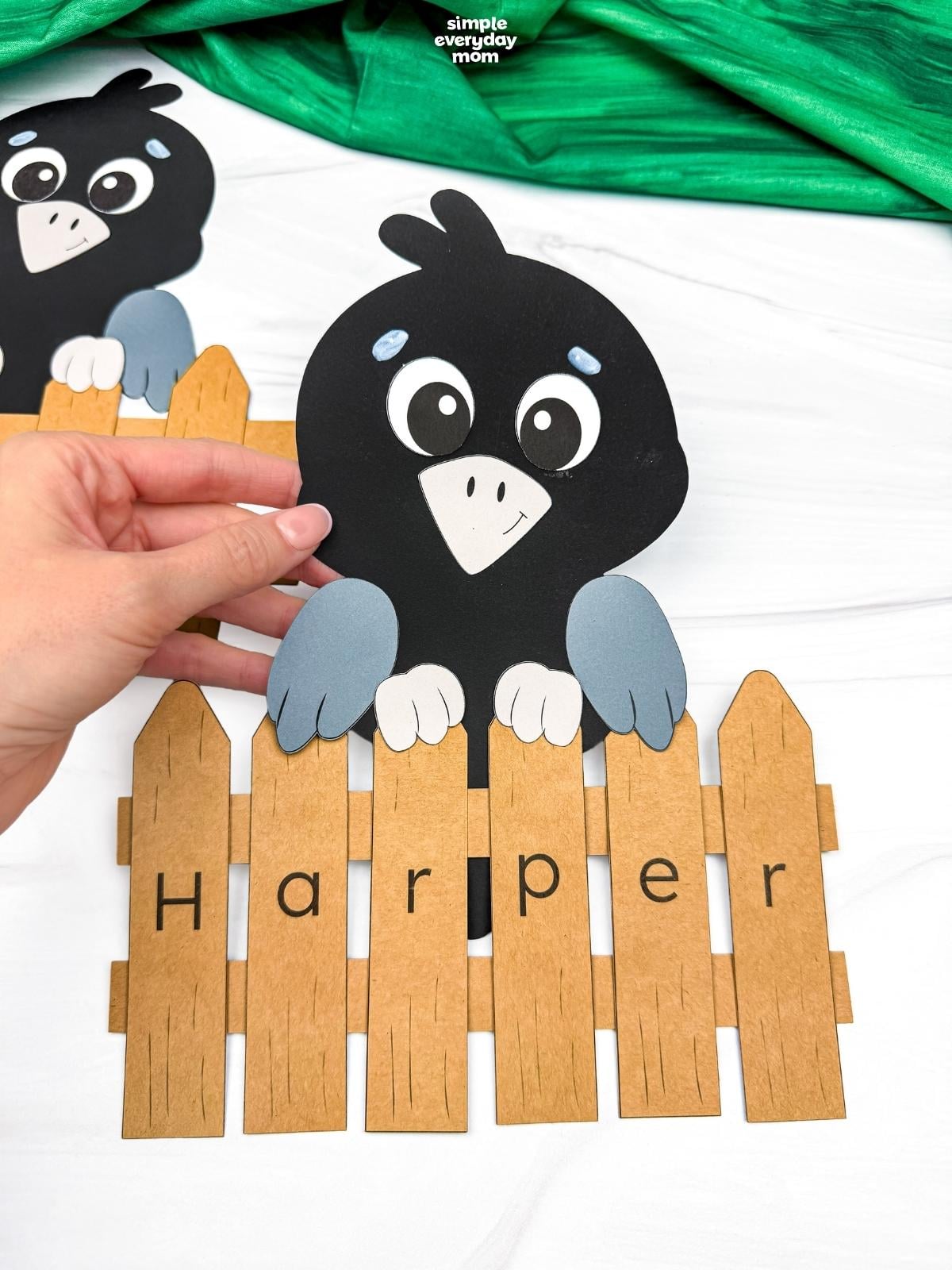 Hands holding a completed Crow Name Craft with a personalized name fence spelling Harper.