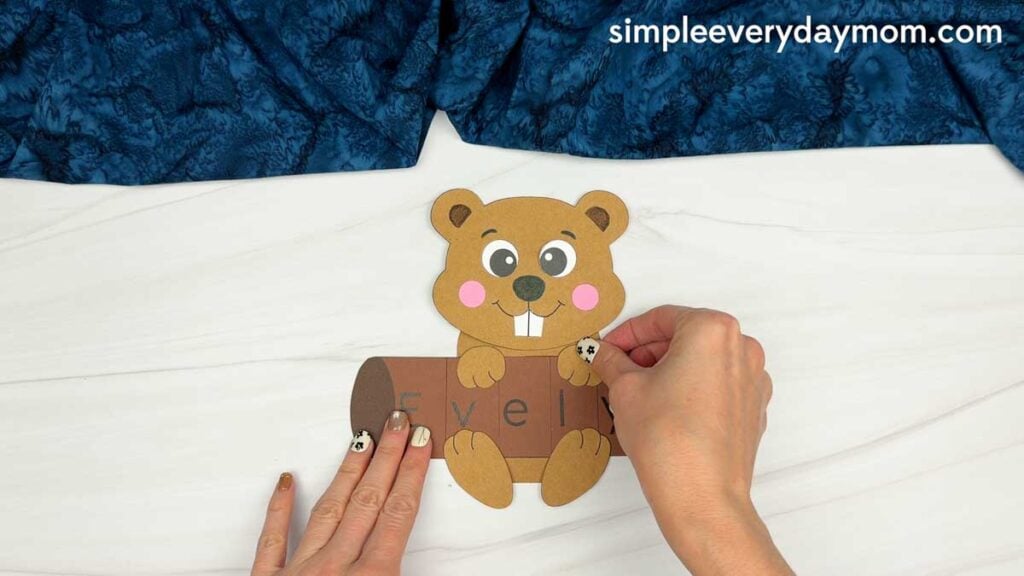 Hands attaching the beaver’s arm over the name log for the Beaver Name Craft.