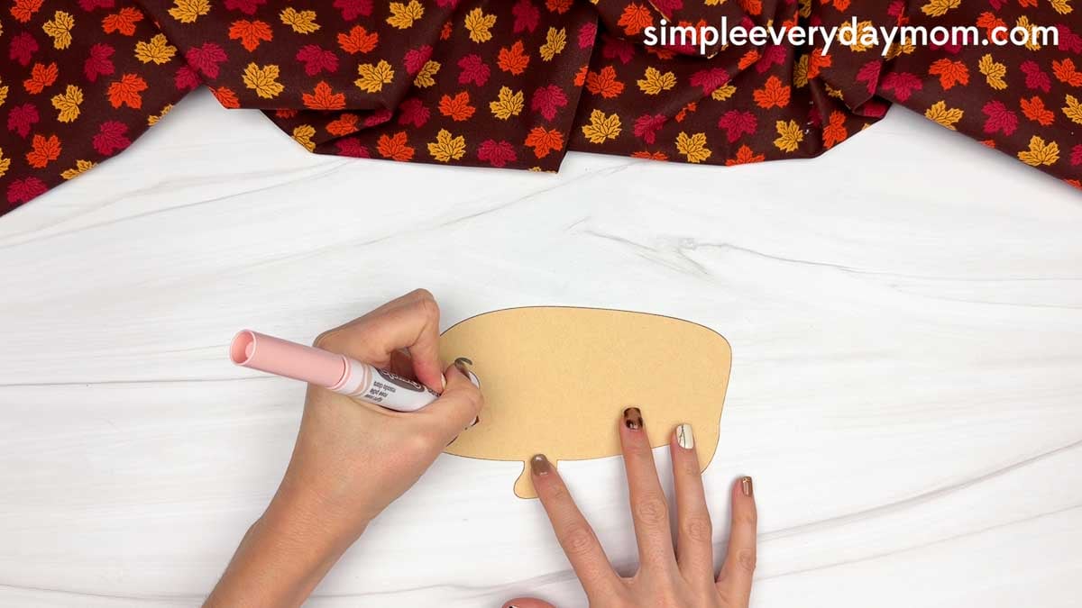 Hands adding a cheek detail to the hedgehog face with a marker.