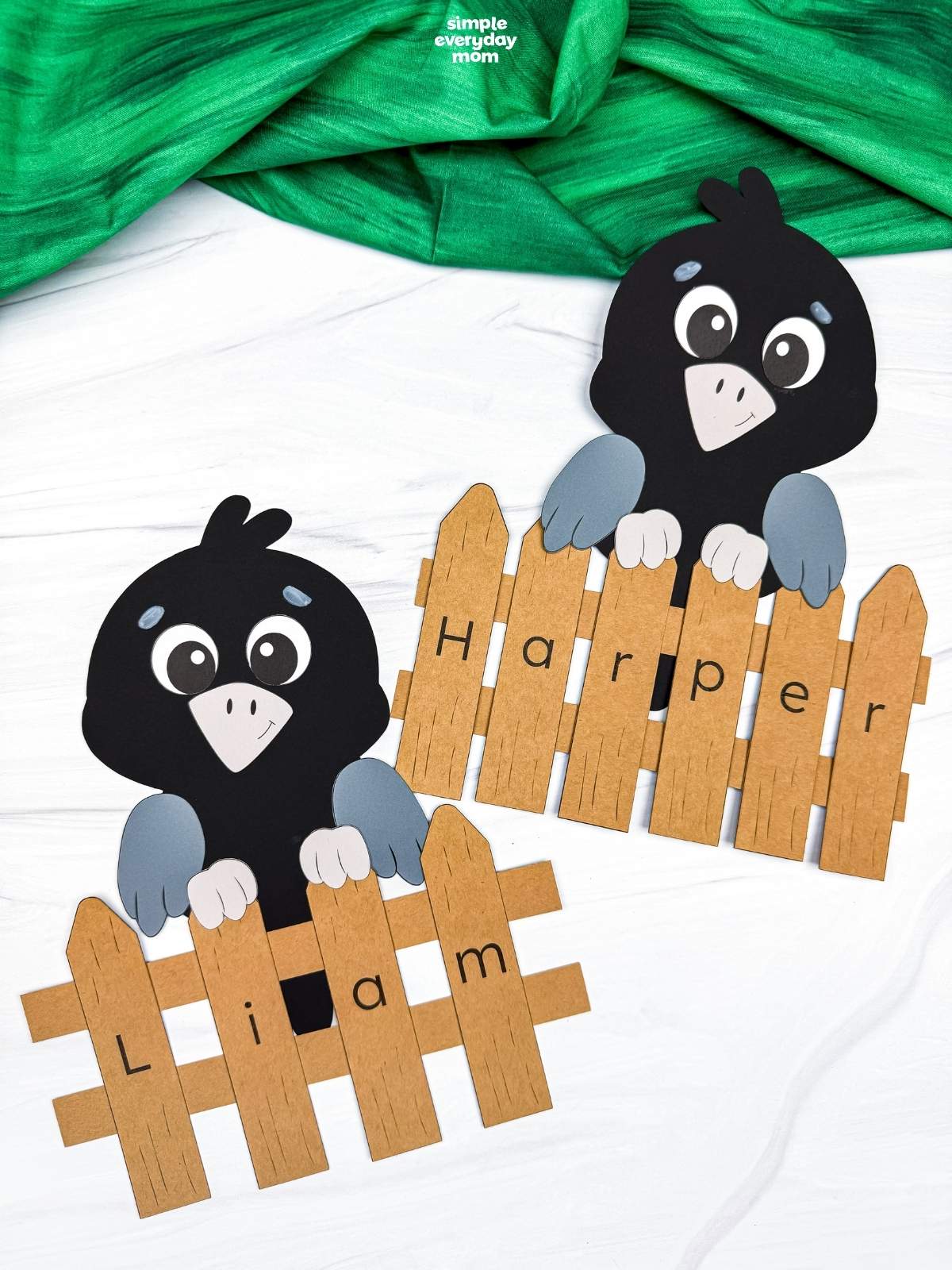 A completed Craft showing two crows behind personalized name fences with letters spelling Liam and Harper.