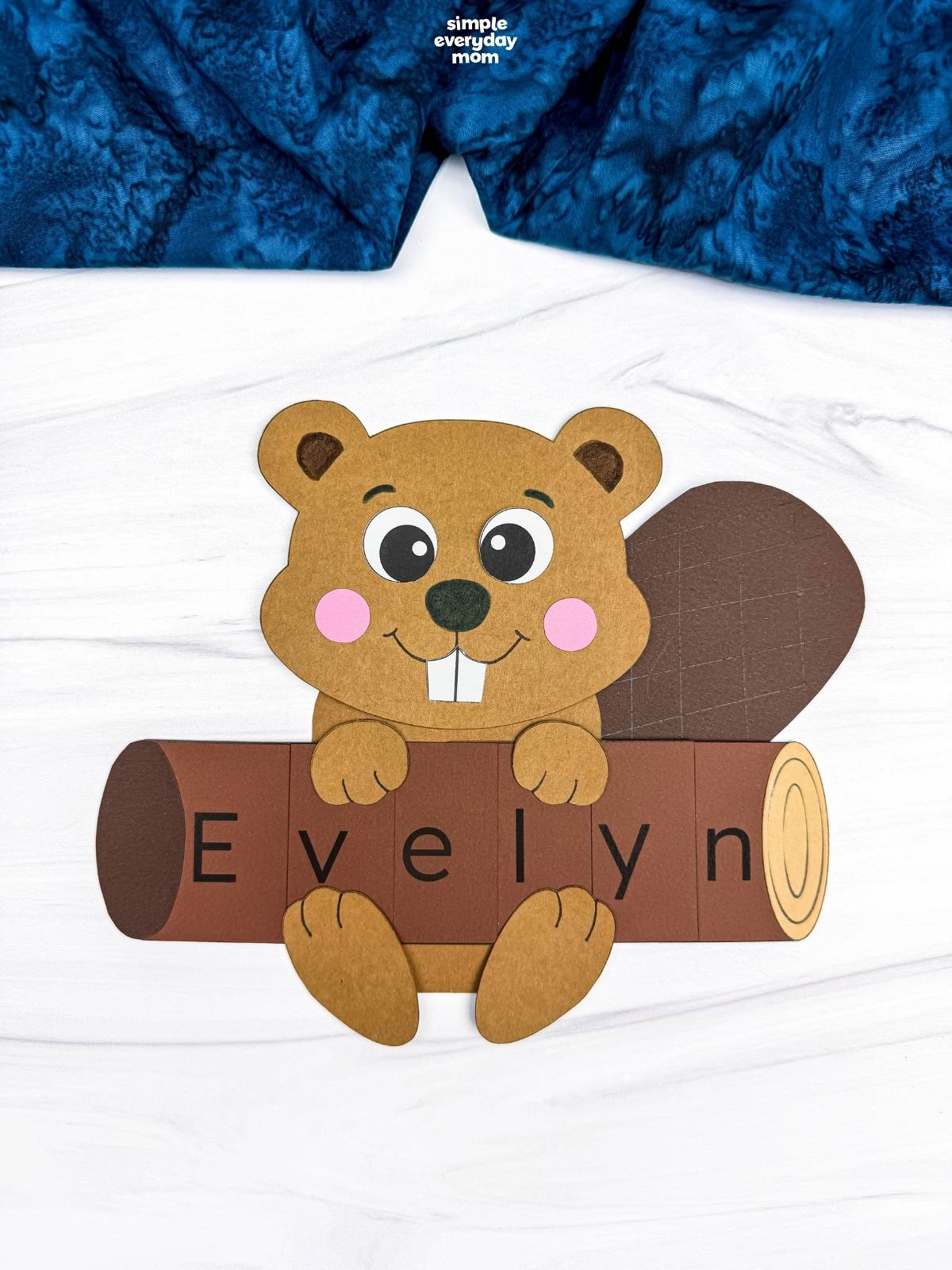 A completed craft showing a beaver holding a log that spells the name Evelyn.
