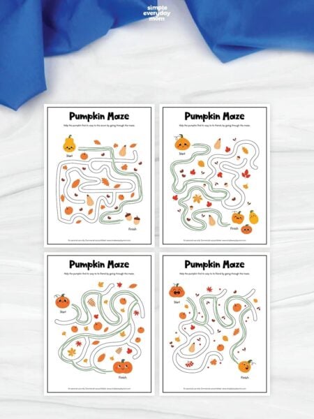 Four printable pumpkin maze worksheets arranged in a grid, each featuring a traced green path through autumn-themed illustrations of pumpkins, leaves, gourds, and acorns.