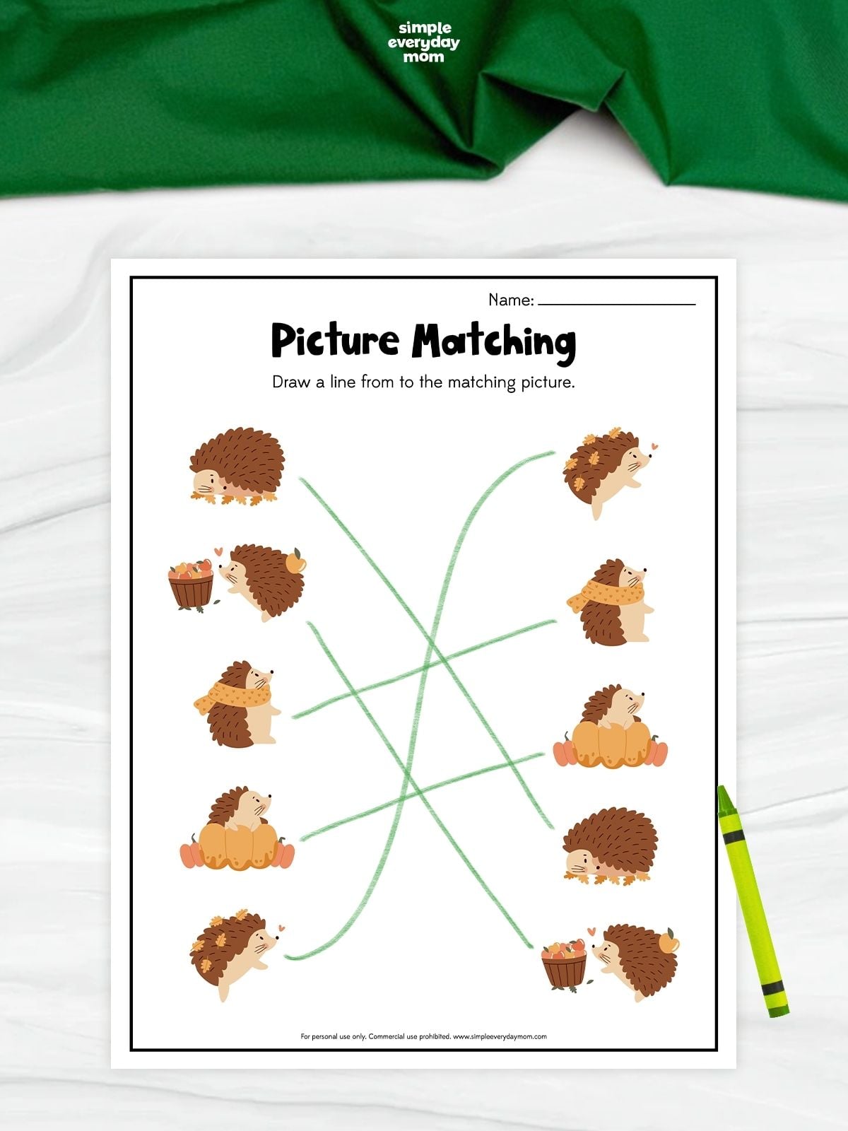 A hedgehog picture matching worksheet with five pairs of fall-themed hedgehog illustrations. Children draw lines to connect matching pictures, including hedgehogs with pumpkins, leaves, scarves, and apples. A green crayon rests beside the completed worksheet.