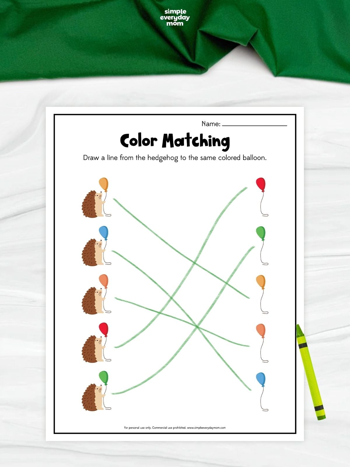 A hedgehog color matching worksheet with five hedgehogs holding red, blue, orange, green, and yellow balloons. Children draw lines to connect each hedgehog to the matching colored balloon. A green crayon rests beside the completed printable.