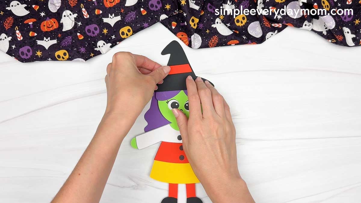 Hands attaching the band across the witch hat.