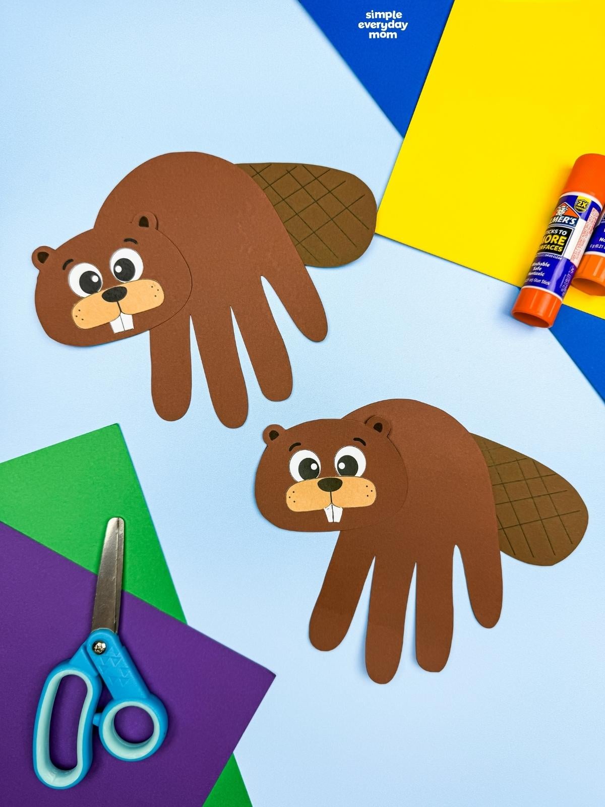 A completed Beaver Handprint Craft displayed with paper, scissors, and a glue stick.