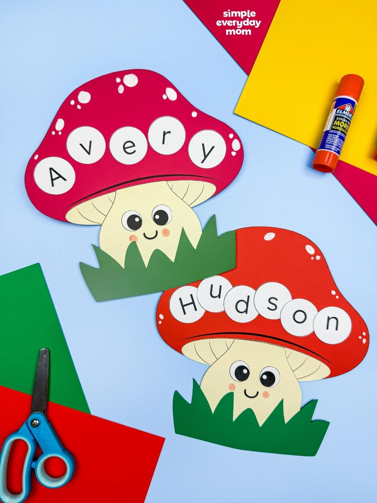 A completed Craft featuring Avery and Hudson mushroom name crafts with colorful paper, scissors, and a glue stick.