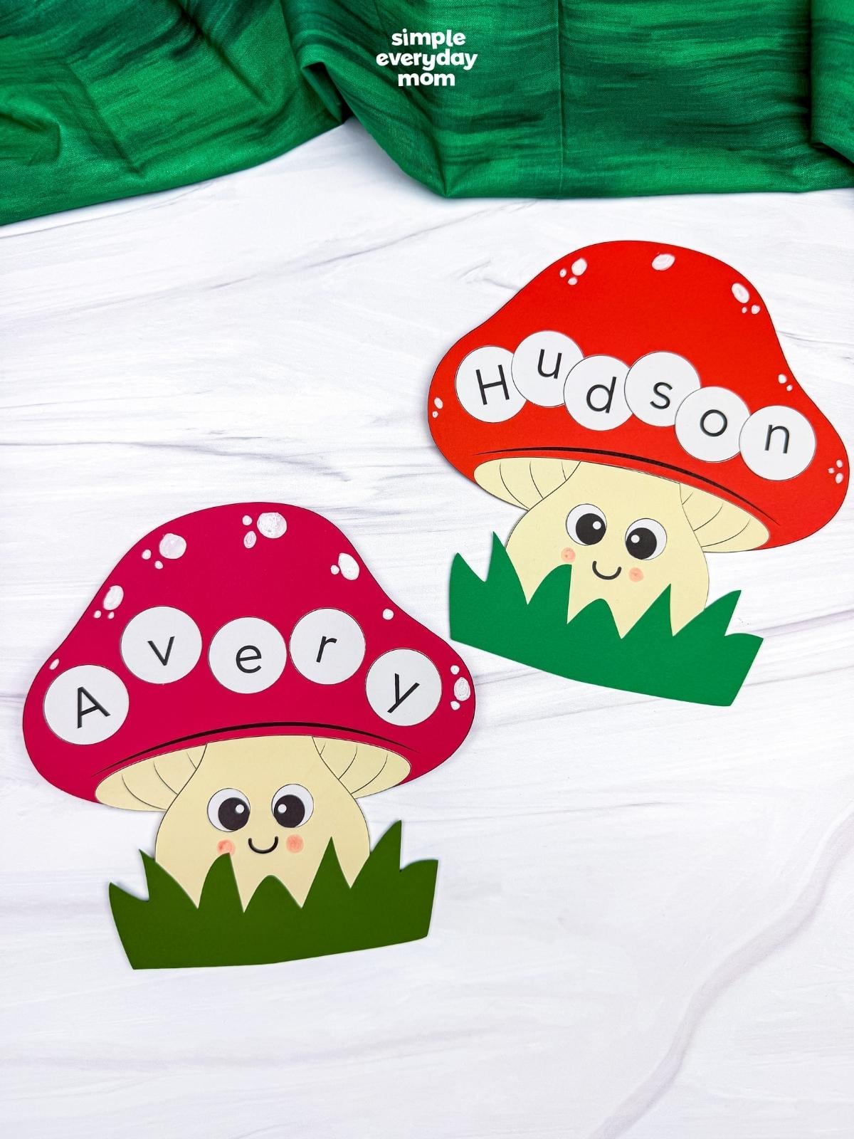 A completed Craft featuring two smiling mushroom name crafts labeled Avery and Hudson with colorful caps and green grass.