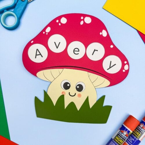 A completed Craft featuring a smiling mushroom name craft spelling Avery, surrounded by scissors, glue sticks, and colorful paper.