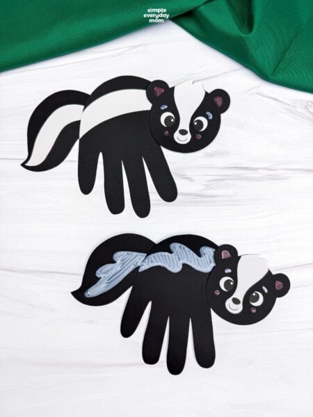 A completed Craft featuring two black skunk handprints with white and silver stripe designs.