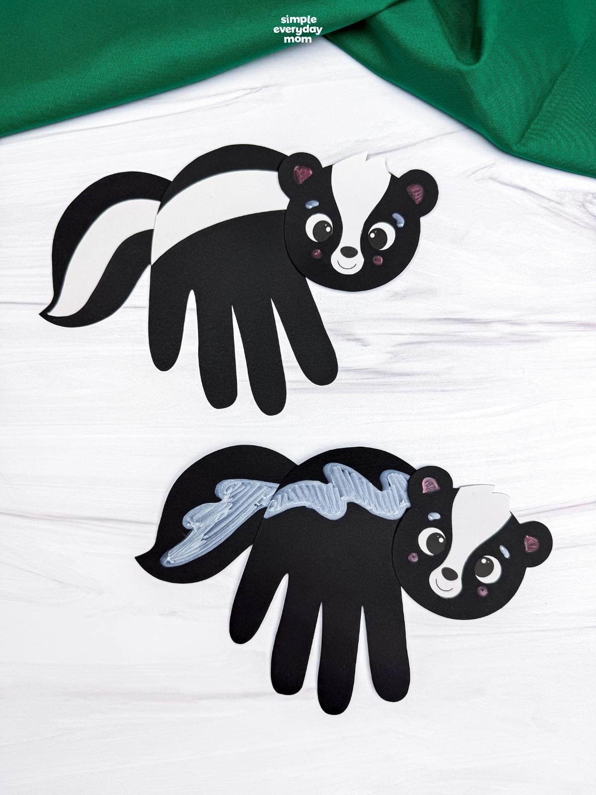 A completed Craft featuring two black skunk handprints with white and silver stripe designs.