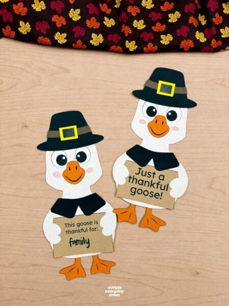 A completed craft featuring two thankful geese wearing pilgrim hats and holding Thanksgiving gratitude signs.