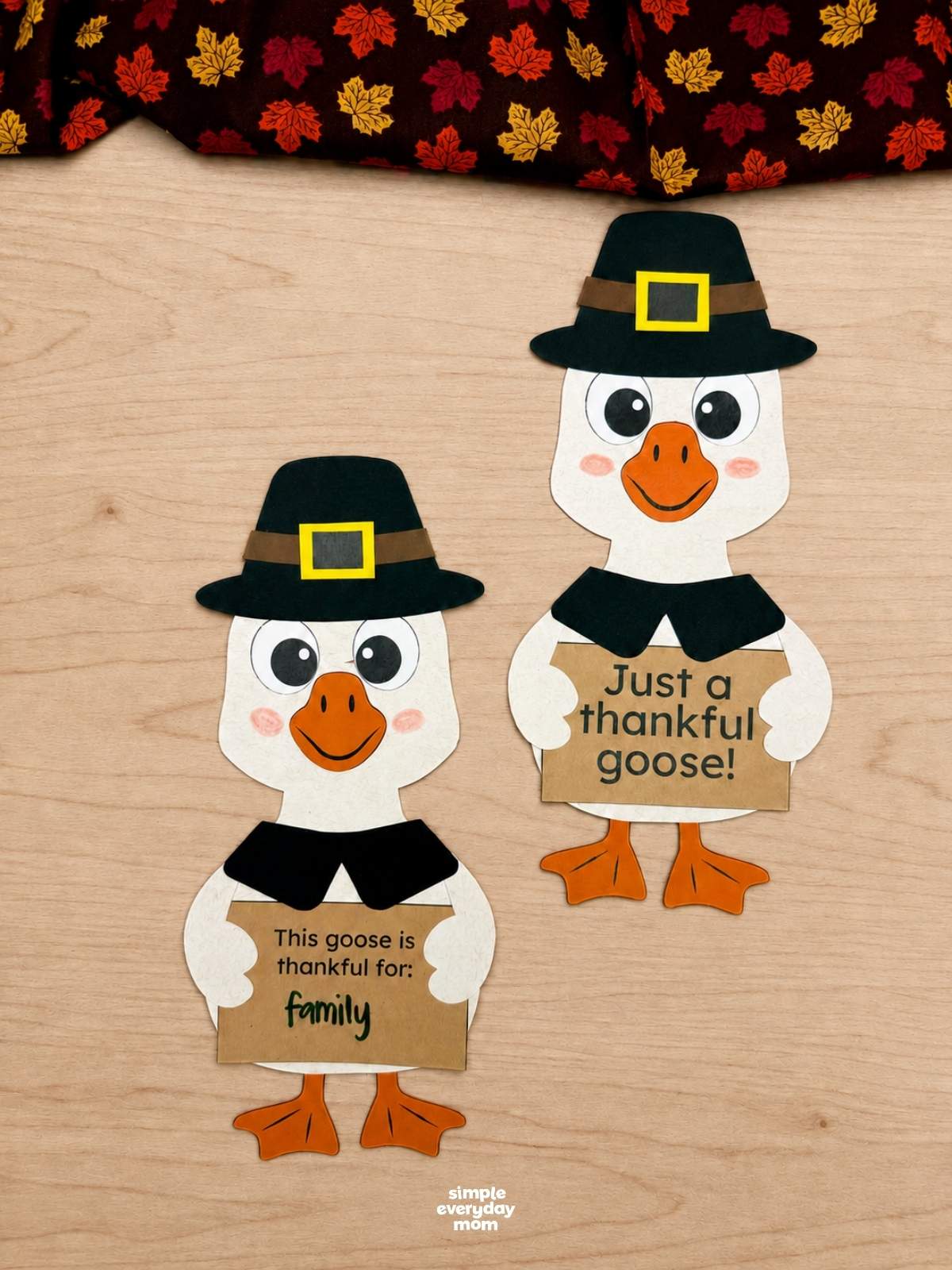 Side by side completed Thankful Goose Crafts wearing pilgrim hats and holding Thanksgiving gratitude signs.