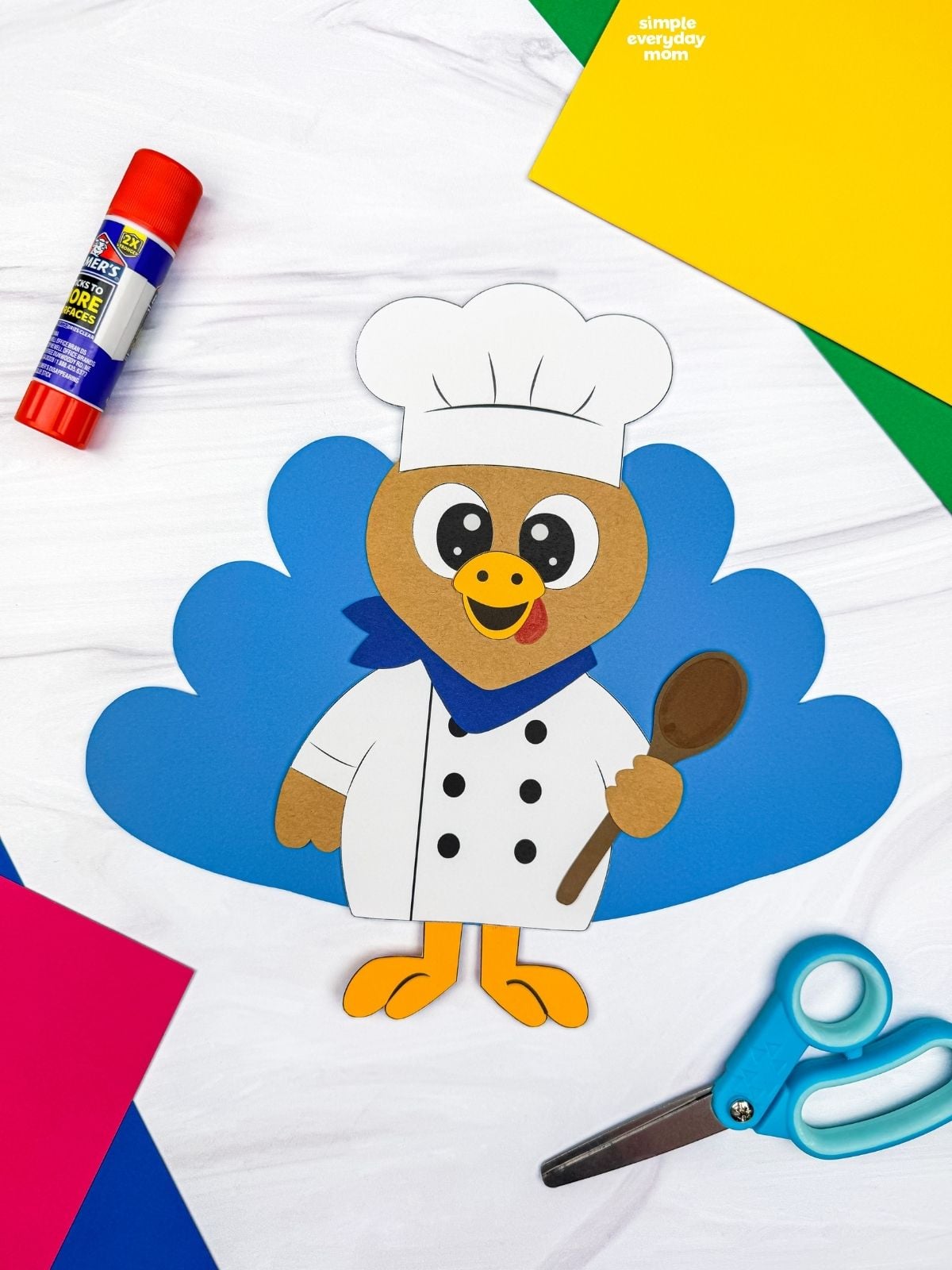 A completed Craft featuring a chef turkey disguise with blue tail feathers, a white chef uniform, and a brown spoon.