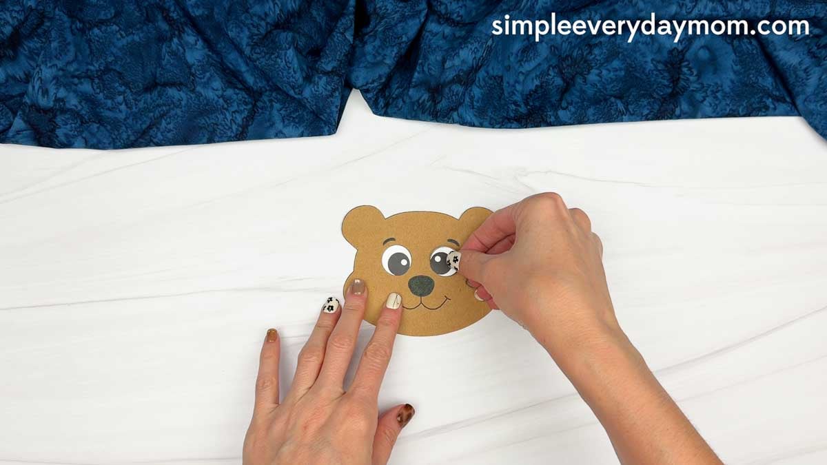 Hands gluing an eye onto the beaver’s face for the Beaver Name Craft.