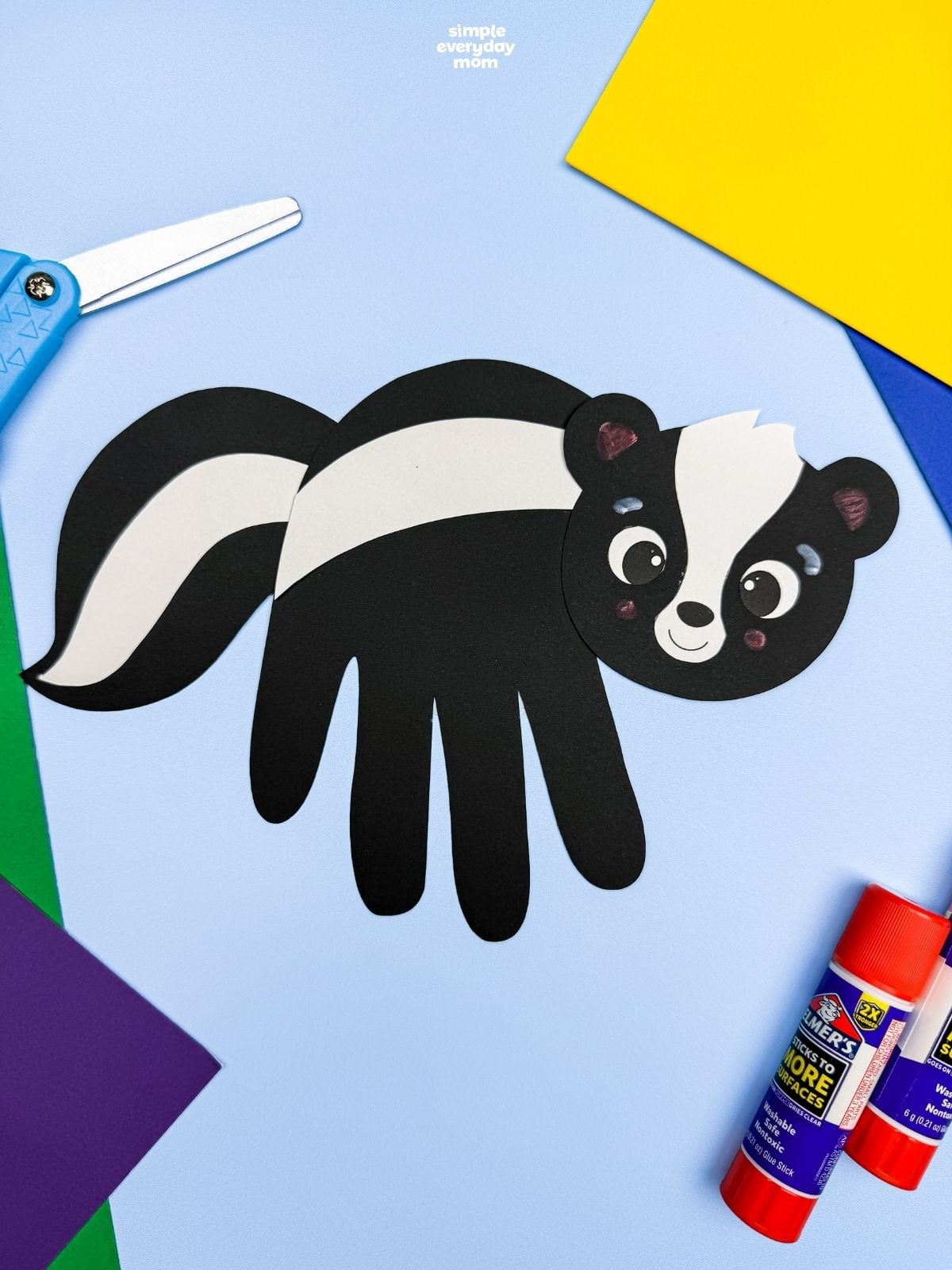 A completed Craft featuring a black handprint skunk with white stripes surrounded by colorful craft supplies.