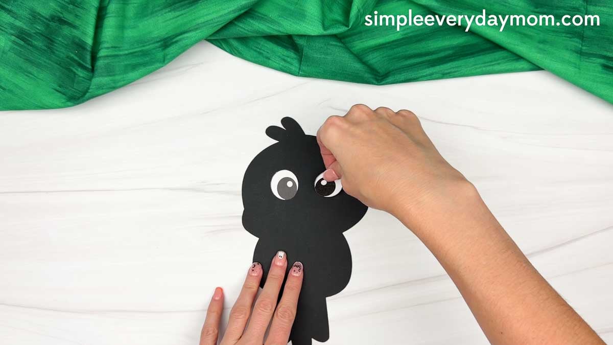 Hands gluing the eyes onto the crow’s head for the Crow Name Craft.