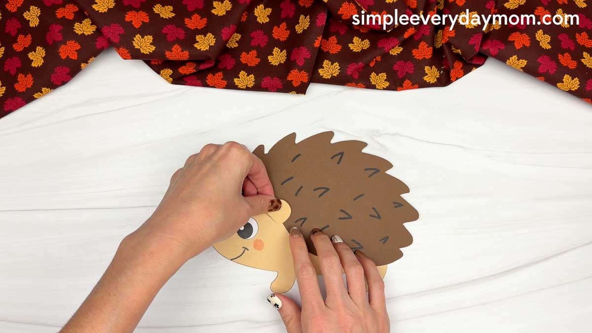 Hands attaching the ear to the hedgehog head below the spiky back piece.