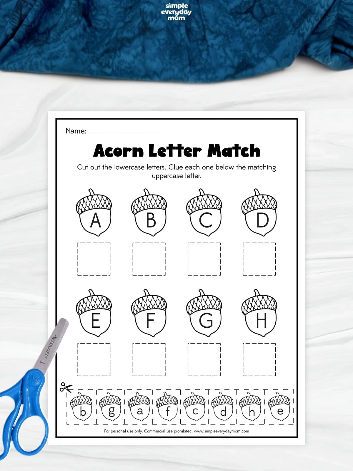 Acorn letter matching worksheet with uppercase letters A–H and cutout lowercase acorns to glue beneath their matching letters, with blue scissors beside the page.