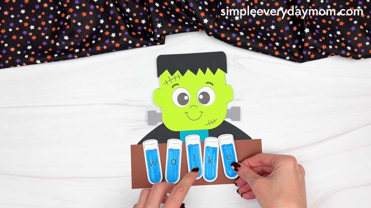 Hands placing the lettered test tubes across the name sign to spell the child’s name.